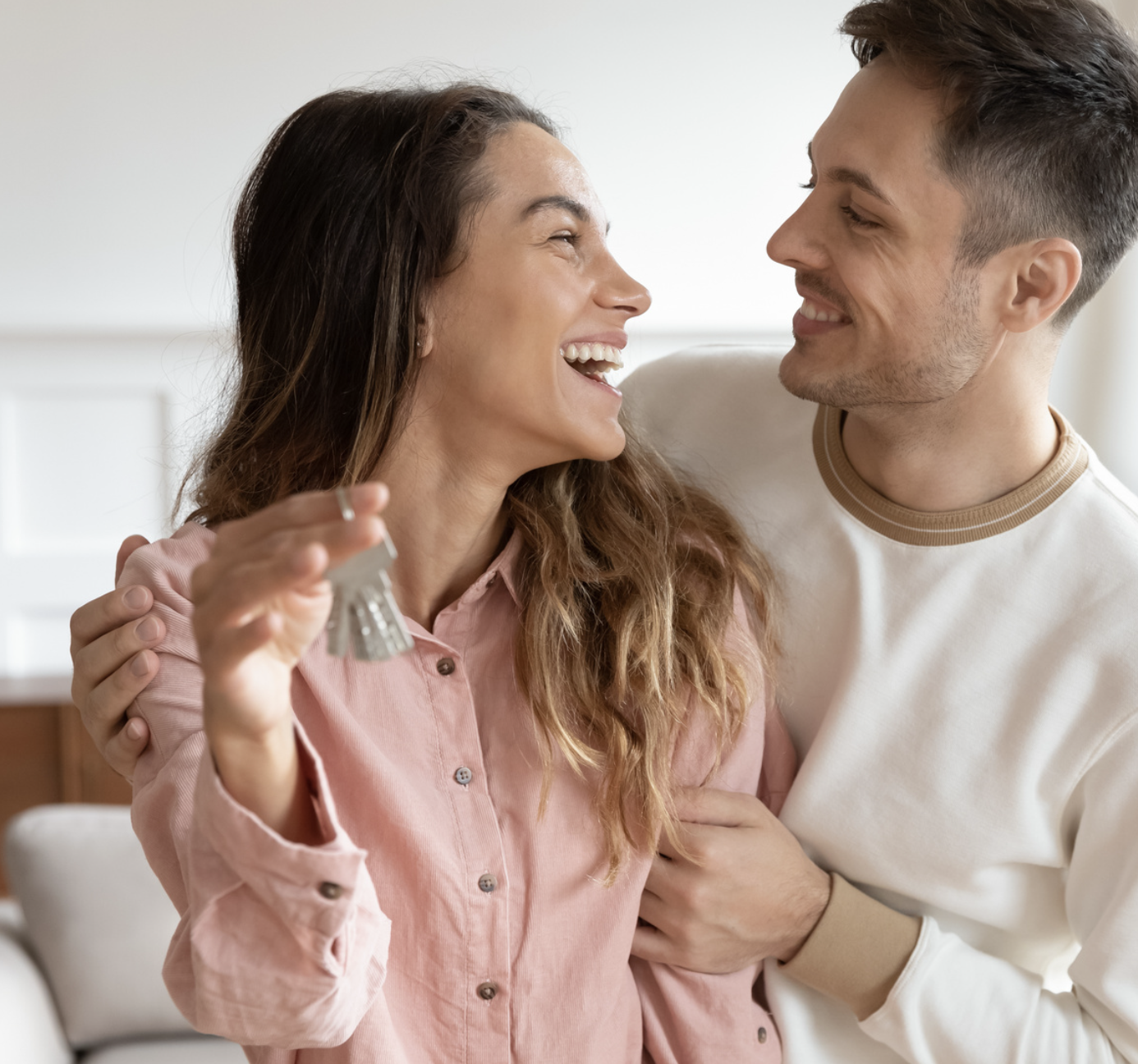 Un couple souriant tient les clés de son nouveau logement