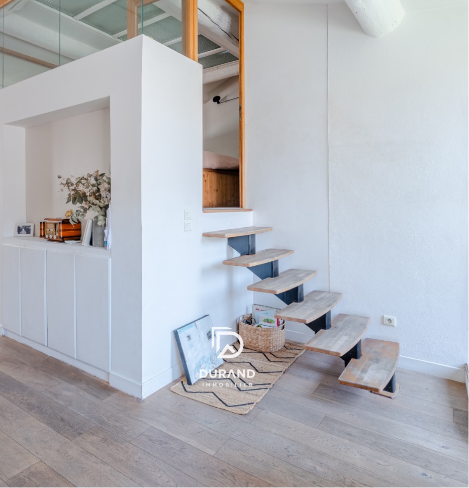 Intérieur lumineux avec escalier en bois d'un appartement géré par Durand Immobilier